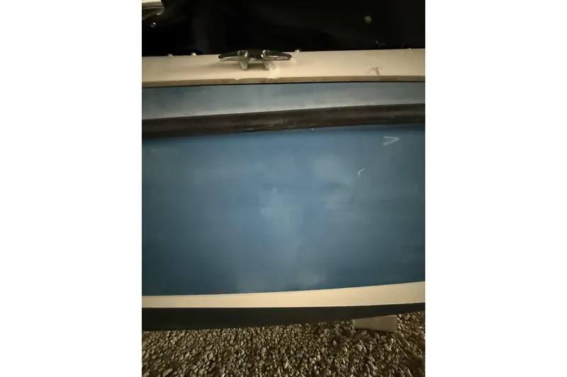 Slide: The Image of 2012 Bayliner 235 Bowrider boat hull in blue, resting on gravel. - 7