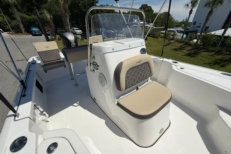 Slide: The Image of 2021 Tidewater 1910 Bay Max boat interior with seating and console, parked outdoors. - 9