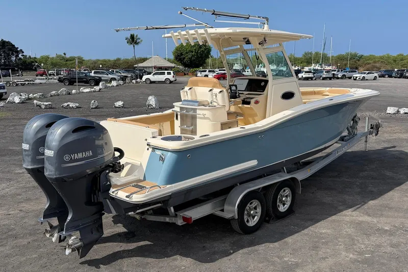 Slide: The Image of 2019 Scout 275 LXF boat with dual Yamaha engines on a trailer in a parking area. - 11