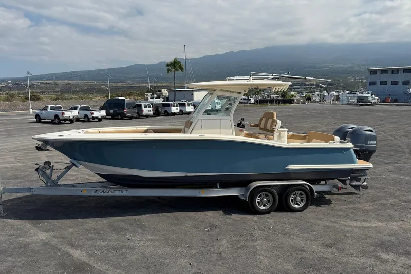 Slide: The Image of 2019 Scout 275 LXF boat on trailer, parked near marina with mountainous backdrop. - 7