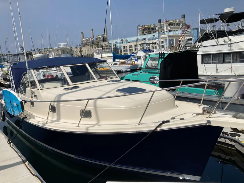 The Image of 2004 Mainship Pilot 34 docked at a marina, surrounded by other boats. - 0