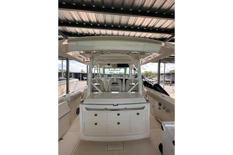 Slide: The Image of 2019 Boston Whaler 380 Outrage boat interior with seating and storage under a covered dock. - 4