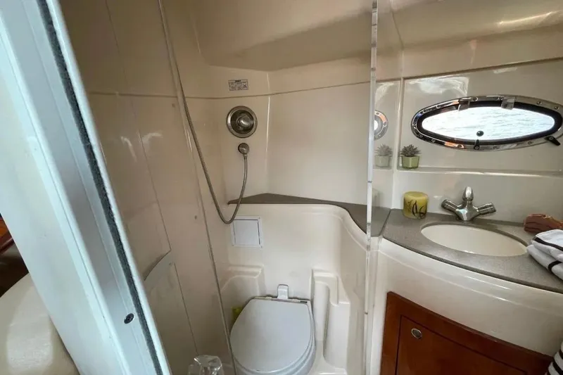 Slide: The Image of 2007 Larson Cabrio 350 boat bathroom with shower, sink, and porthole window. - 12