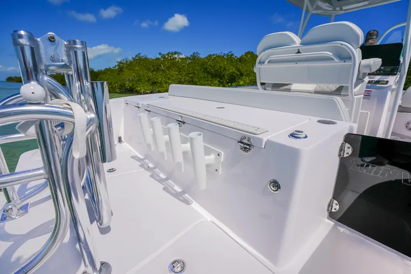 Slide: The Image of 2026 Twin Vee 240 GFX CC boat deck with rod holders and seating, under clear blue sky. - 17
