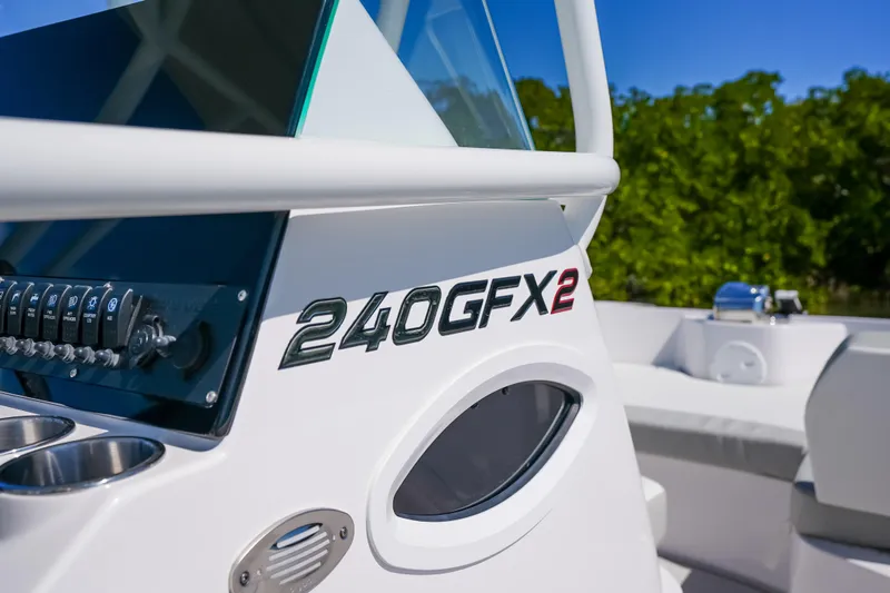 Slide: The Image of 2026 Twin Vee 240 GFX CC boat console with controls and branding, set against a natural backdrop. - 19