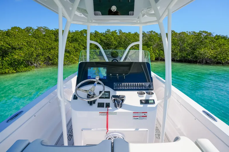 Slide: The Image of Twin Vee 240 GFX CC 2026 boat navigating clear turquoise waters near lush greenery. - 21