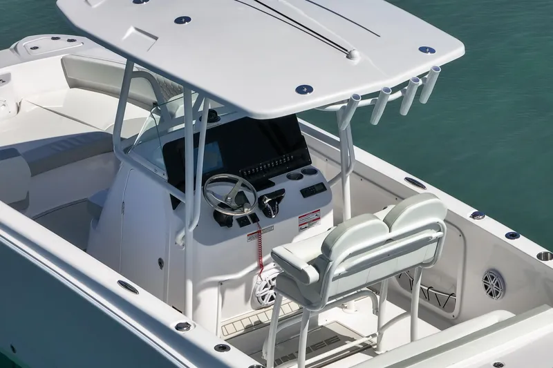 Slide: The Image of 2026 Twin Vee 240 GFX CC boat interior with helm and seating, on calm water. - 40