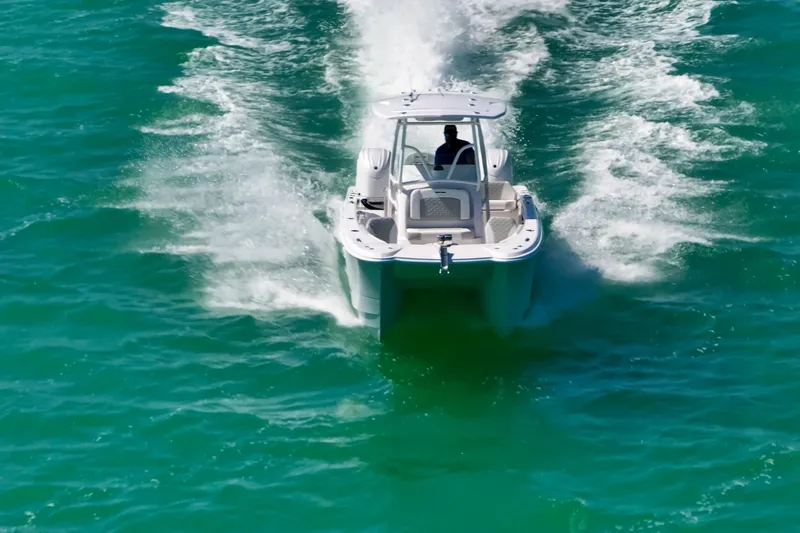 Slide: The Image of 2026 Twin Vee 240 GFX CC boat cruising on turquoise water, rear view. - 8