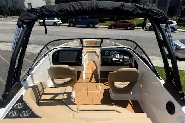 Slide: The Image of 2026 Bayliner V20i boat interior with tan seating and modern dashboard, parked on street. - 25