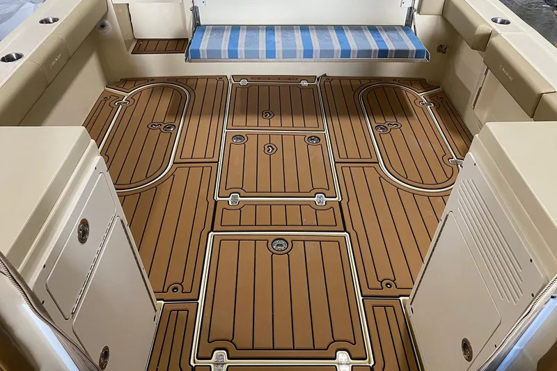 Slide: The Image of Manufacturer Provided Image: 2025 NorthCoast 315 HT boat interior with teak-style flooring and blue-striped seating. - 10