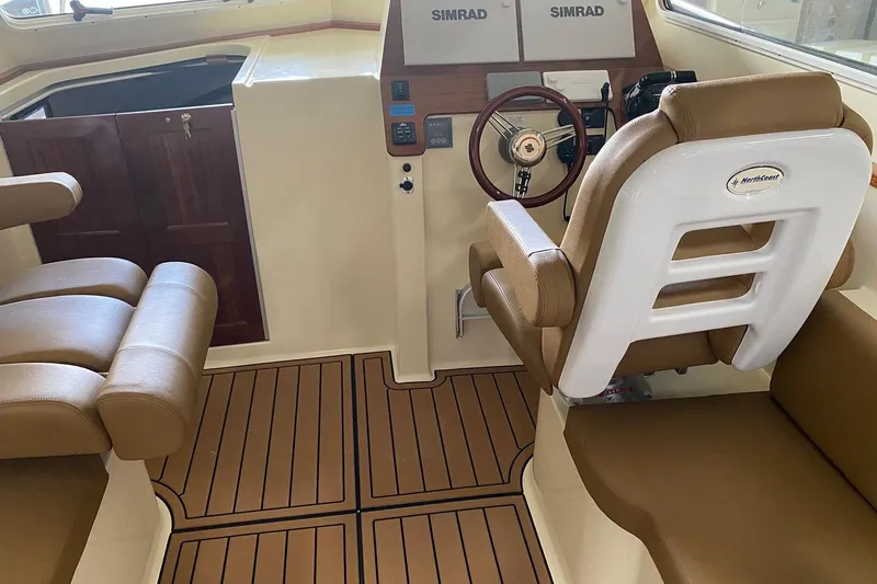 Slide: The Image of Manufacturer Provided Image: 2025 NorthCoast 315 HT boat interior with Simrad controls and brown seating. - 7