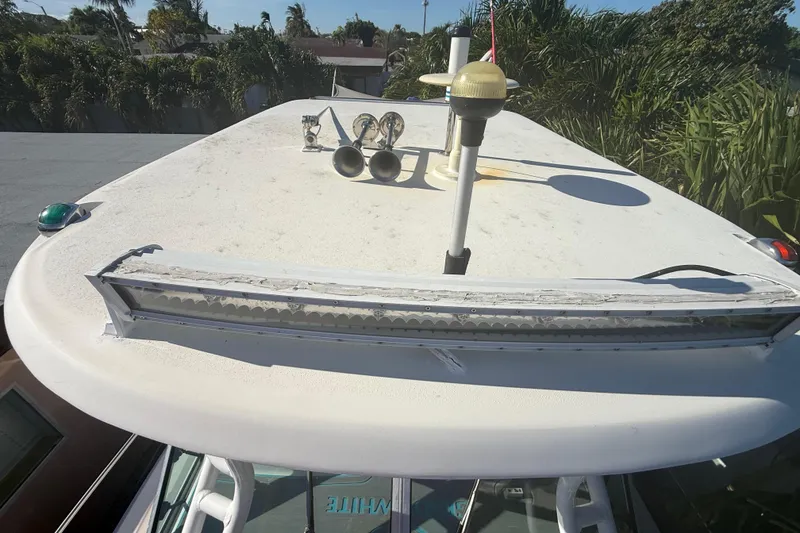 Slide: The Image of 1996 Grady-White Sailfish 272 boat roof with antennas and horns, surrounded by greenery. - 105