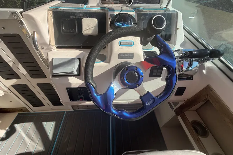 Slide: The Image of 1996 Grady-White Sailfish 272 boat helm with blue steering wheel and control panel. - 47