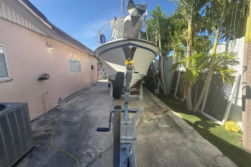 Slide: The Image of 1996 Grady-White Sailfish 272 boat on trailer beside house and palm trees. - 6