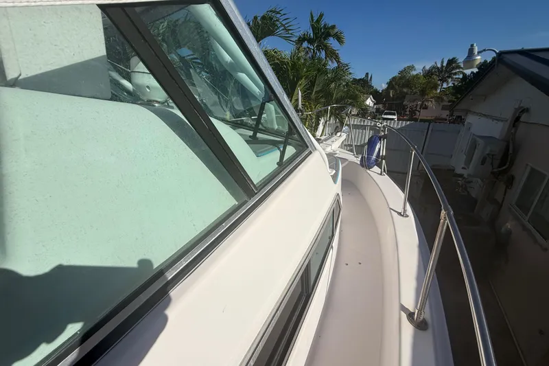 Slide: The Image of 1996 Grady-White Sailfish 272 boat deck with railing and windows, docked near palm trees. - 91