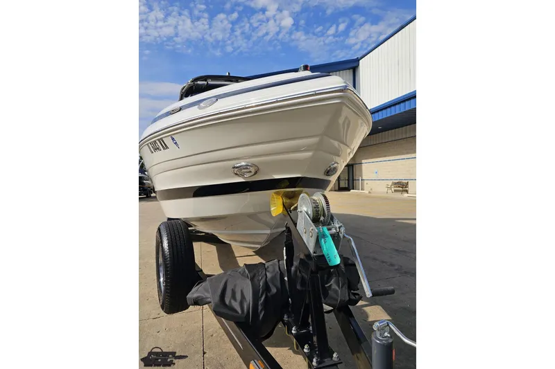 Slide: The Image of 2019 Crownline 275 SS boat on trailer, parked outside a building under a blue sky. - 19