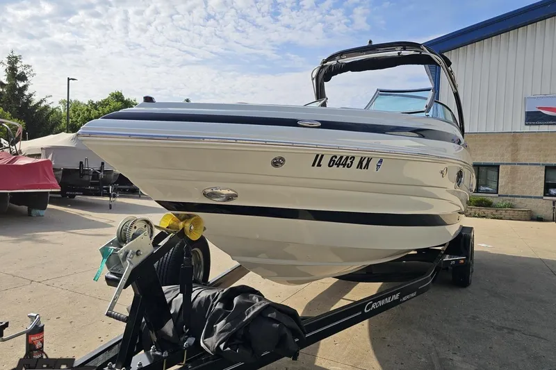 Slide: The Image of 2019 Crownline 275 SS boat on trailer, parked outdoors under a partly cloudy sky. - 23