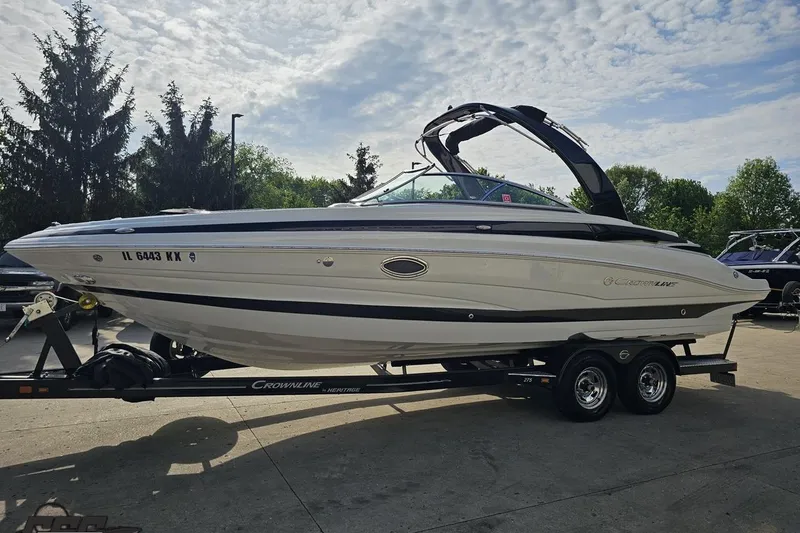 Slide: The Image of 2019 Crownline 275 SS boat on trailer, parked outdoors under cloudy sky. - 25