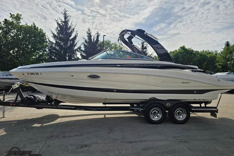 Slide: The Image of 2019 Crownline 275 SS boat on trailer, parked outdoors under a cloudy sky. - 26