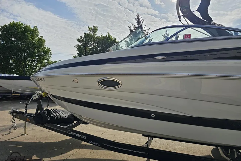 Slide: The Image of 2019 Crownline 275 SS boat on trailer, parked outdoors under a cloudy sky. - 27