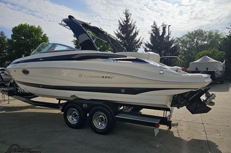 Slide: The Image of 2019 Crownline 275 SS boat on trailer, parked outdoors under a partly cloudy sky. - 32