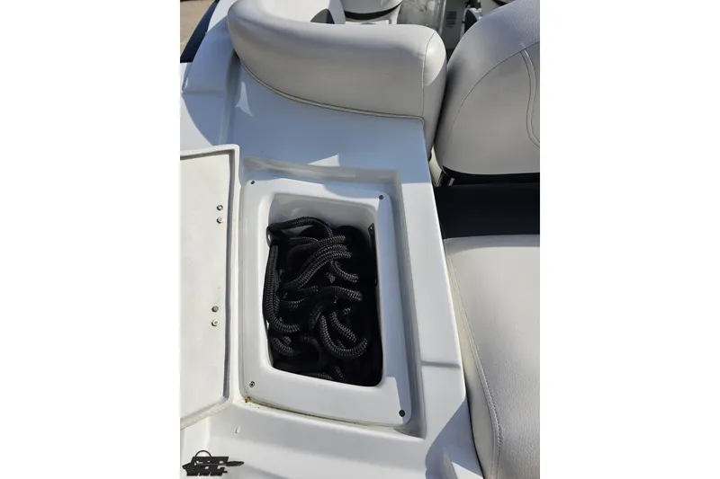 Slide: The Image of 2019 Crownline 275 SS boat storage compartment with coiled rope on white seating. - 47