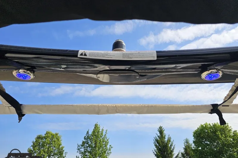 Slide: The Image of 2019 Crownline 275 SS boat canopy with blue LED lights against a clear sky. - 61