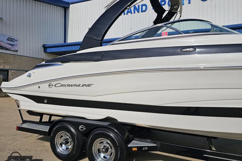 Slide: The Image of 2019 Crownline 275 SS boat on trailer at dealership, showcasing sleek design and branding. - 8