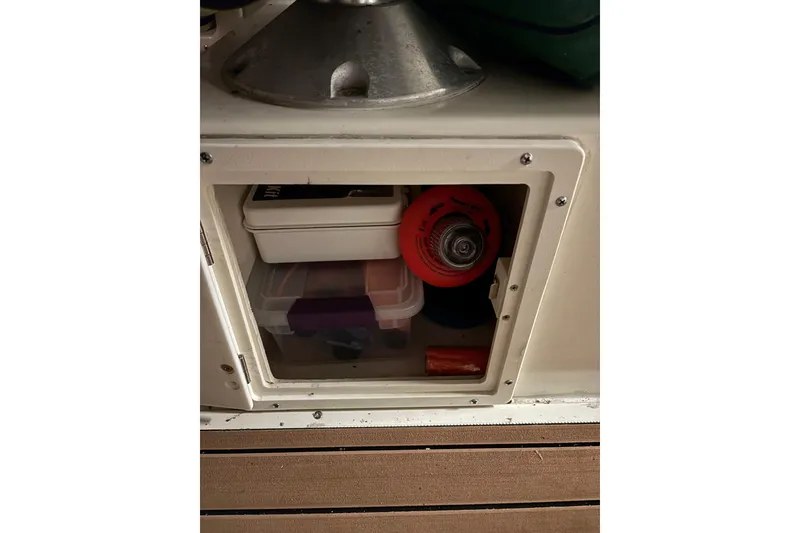 Slide: The Image of Storage compartment on a 1999 Pursuit 2460 Denali boat with various items inside. - 11