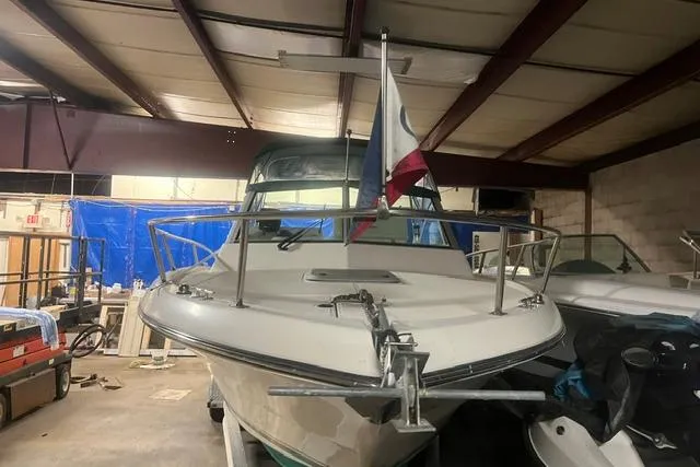 Slide: The Image of 1999 Pursuit 2460 Denali boat in storage, featuring a flag and anchor. - 19