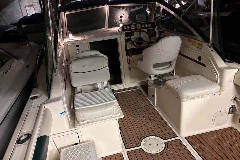 Slide: The Image of 1999 Pursuit 2460 Denali boat interior with white seating and wooden flooring. - 2