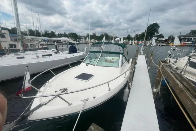 Slide: The Image of 1999 Pursuit 2460 Denali boat docked at a marina under cloudy skies. - 21