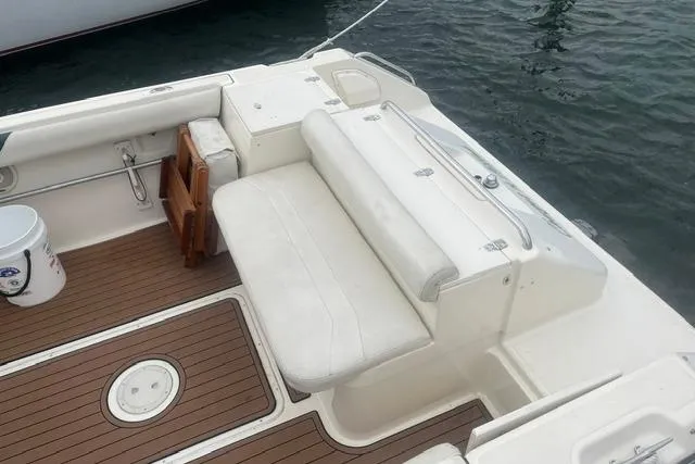 Slide: The Image of 1999 Pursuit 2460 Denali boat interior with white seating and wooden deck. - 22