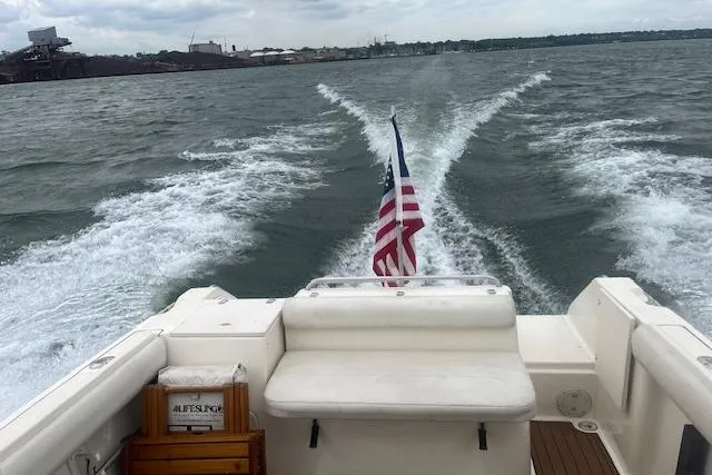 Slide: The Image of 1999 Pursuit 2460 Denali boat cruising on open water with American flag. - 23