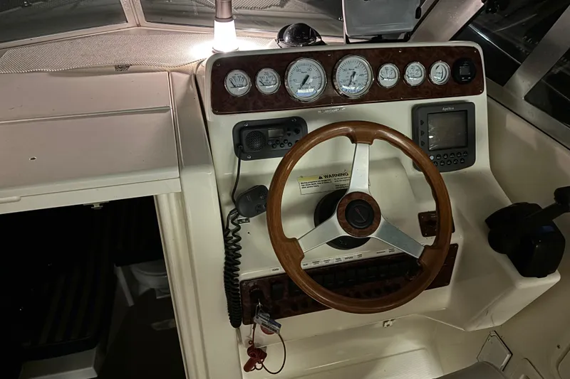 Slide: The Image of 1999 Pursuit 2460 Denali boat dashboard with gauges, steering wheel, and navigation equipment. - 3