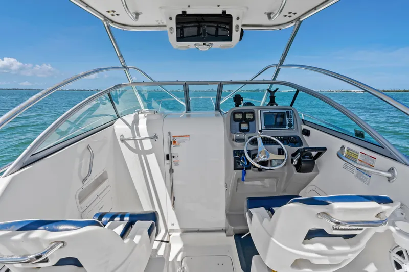 Slide: The Image of 2009 Robalo R245 Walkaround boat cockpit with steering wheel and navigation equipment on open water. - 17