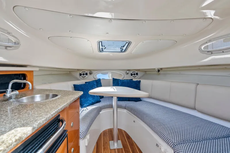 Slide: The Image of 2009 Robalo R245 Walkaround cabin interior with seating, table, and kitchenette. - 18