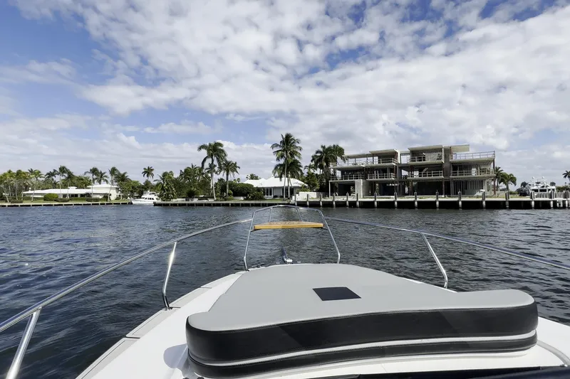 Slide: The Image of Bow view from Hanover 305 yacht, 2027 model, cruising near waterfront homes and palm trees. - 12