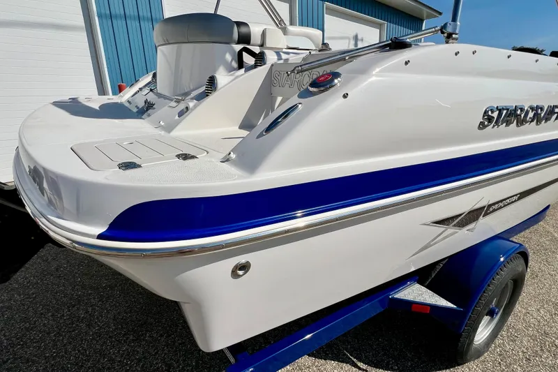 Slide: The Image of 2014 Starcraft 2000 IO Limited boat with blue accents on a trailer. - 3