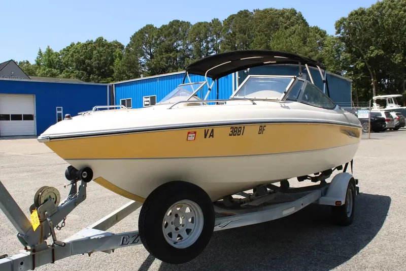Slide: The Image of 2004 Stingray 180 LX boat on trailer, yellow and white, parked outdoors. - 4