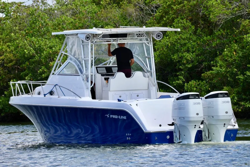 Slide: The Image of 2002 Pro-Line 32 Express boat with dual Suzuki engines on a calm waterway. - 2