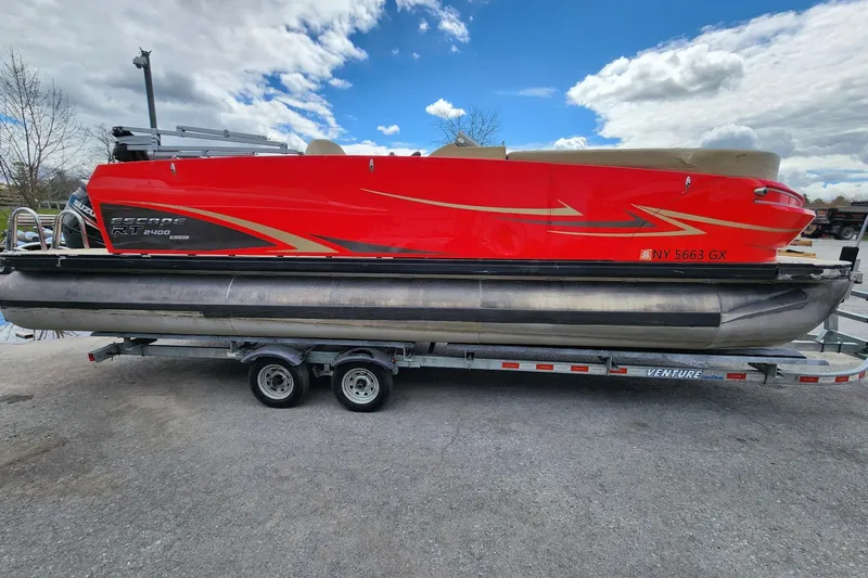 The Image of 2017 Larson Escape RT 2400 Cruise Triple pontoon boat on trailer, vibrant red design. - 1