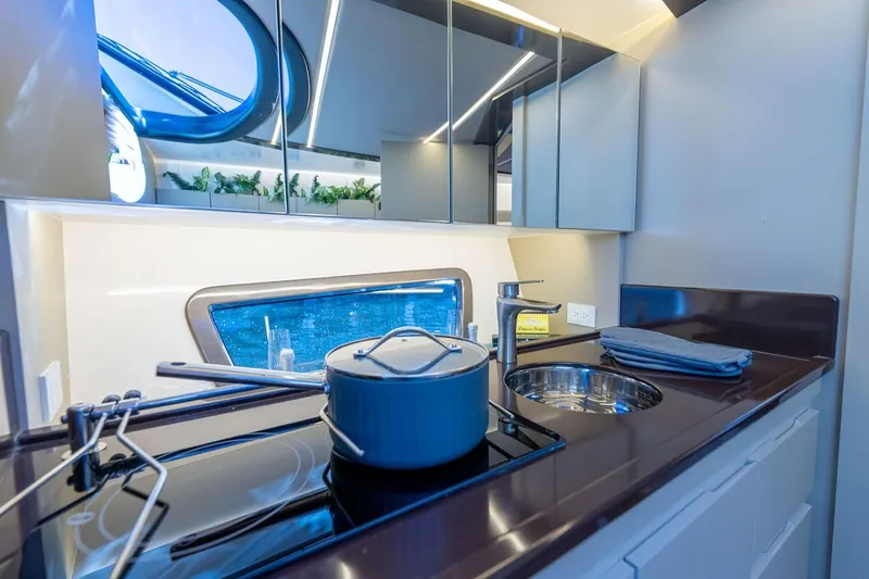 Slide: The Image of Manufacturer Provided Image: Modern yacht kitchen interior with sleek design, featuring stove, sink, and window view. Hanover 415, 2025. - 9