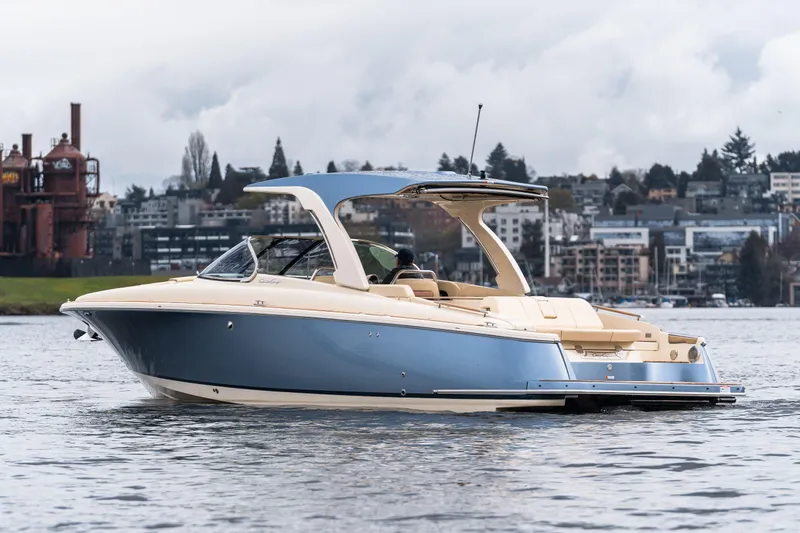 Slide: The Image of 2025 Chris-Craft Launch 31 GT boat on water, cityscape background, overcast sky. - 2