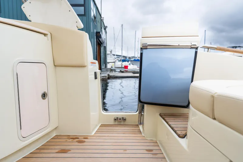 Slide: The Image of 2025 Chris-Craft Launch 31 GT boat interior with teak flooring and marina view. - 20