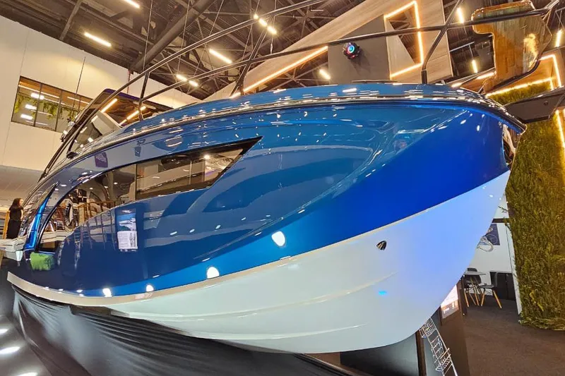 Slide: The Image of 2027 Hanover 327 boat showcased indoors, featuring sleek blue and white design. - 22