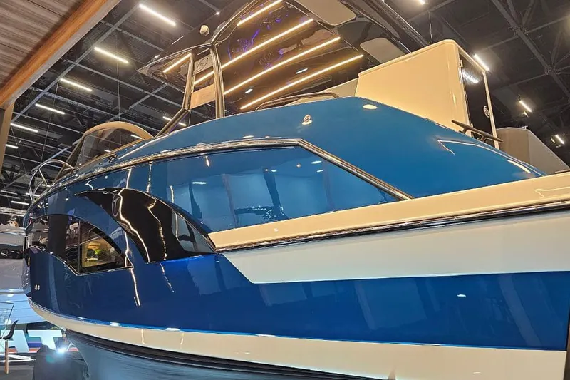 Slide: The Image of 2027 Hanover 327 boat showcased indoors with sleek blue and white design. - 28