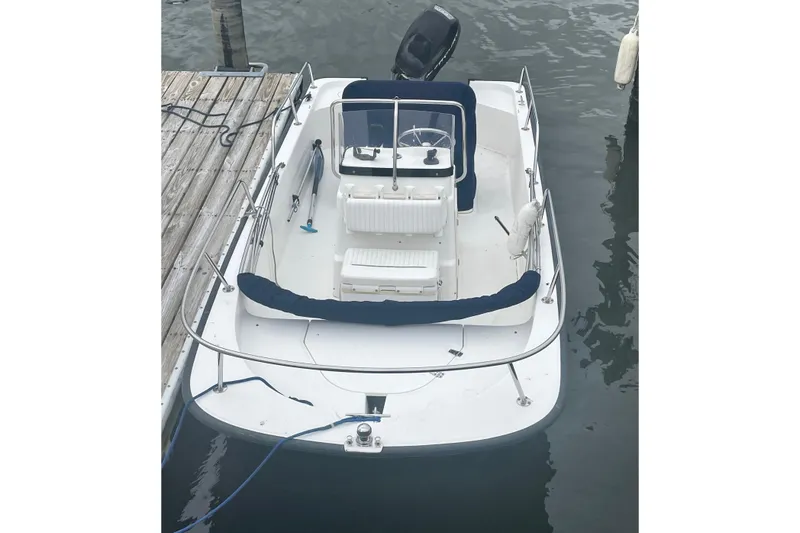 Slide: The Image of 2009 Boston Whaler 150 Montauk boat docked, featuring white and blue seating. - 3
