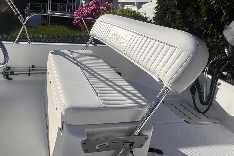 Slide: The Image of 2009 Boston Whaler 150 Montauk boat interior with white cushioned seating. - 6