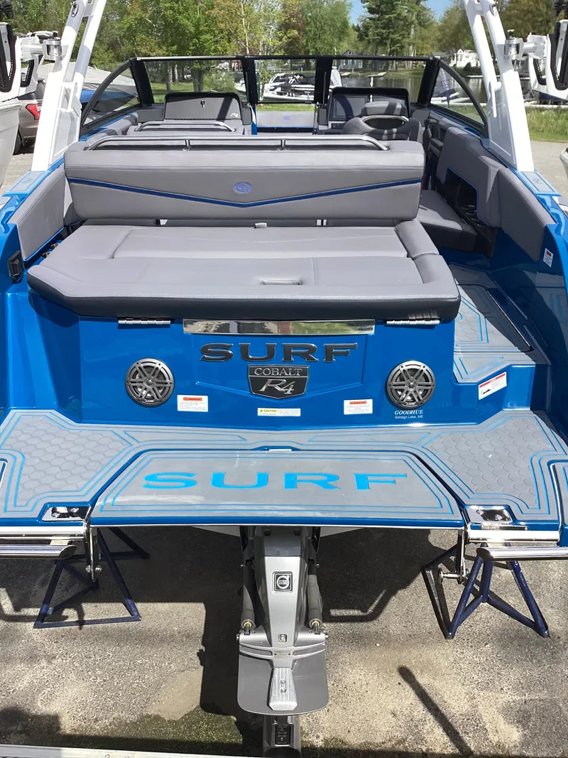 Slide: The Image of Rear view of blue 2026 Cobalt R4 Surf boat with gray seating. - 4